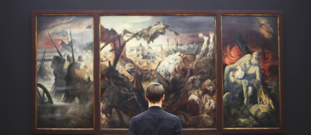 A man in a dark suit viewed from behind, contemplating a triptych of dramatic classical paintings mounted on a wall. The paintings appear to depict historical or mythological scenes with figures in battle or dramatic poses.