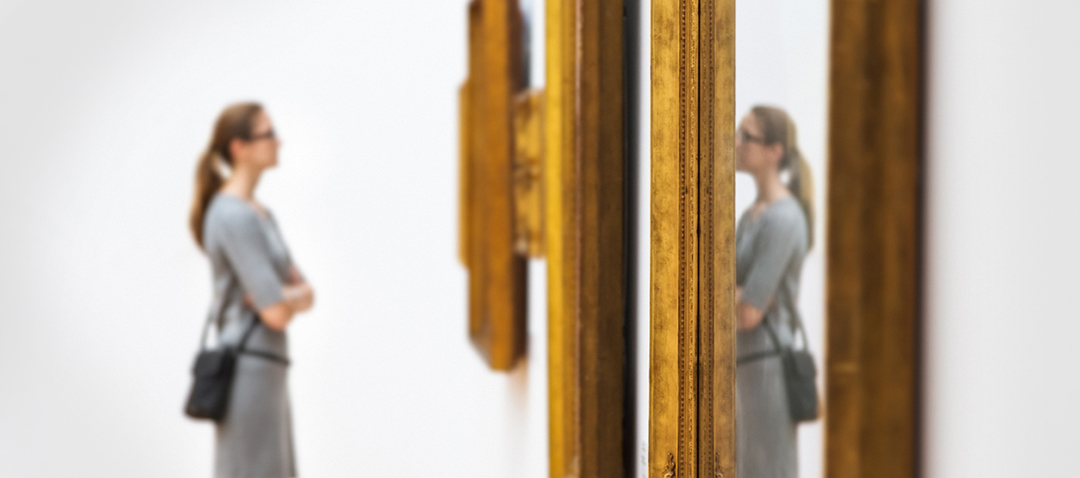 Visitor viewing antique frames at a gallery, showcasing the sustained interest in art and antiques among high-net-worth collectors