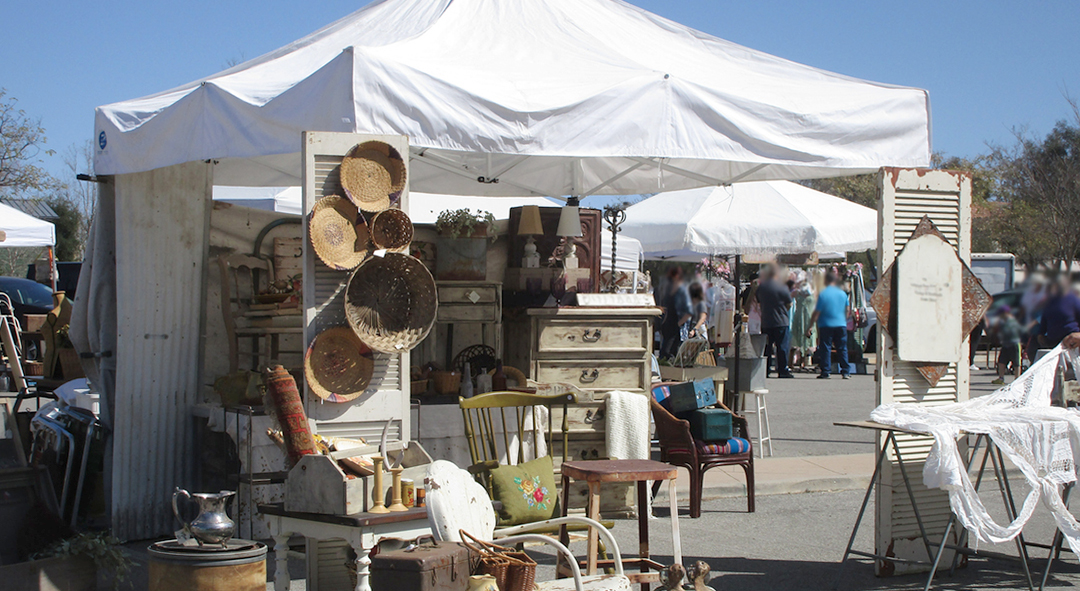 Outdoor antiques fair with vintage furniture and collectibles display, demonstrating the thriving marketplace for secondhand and estate sale items