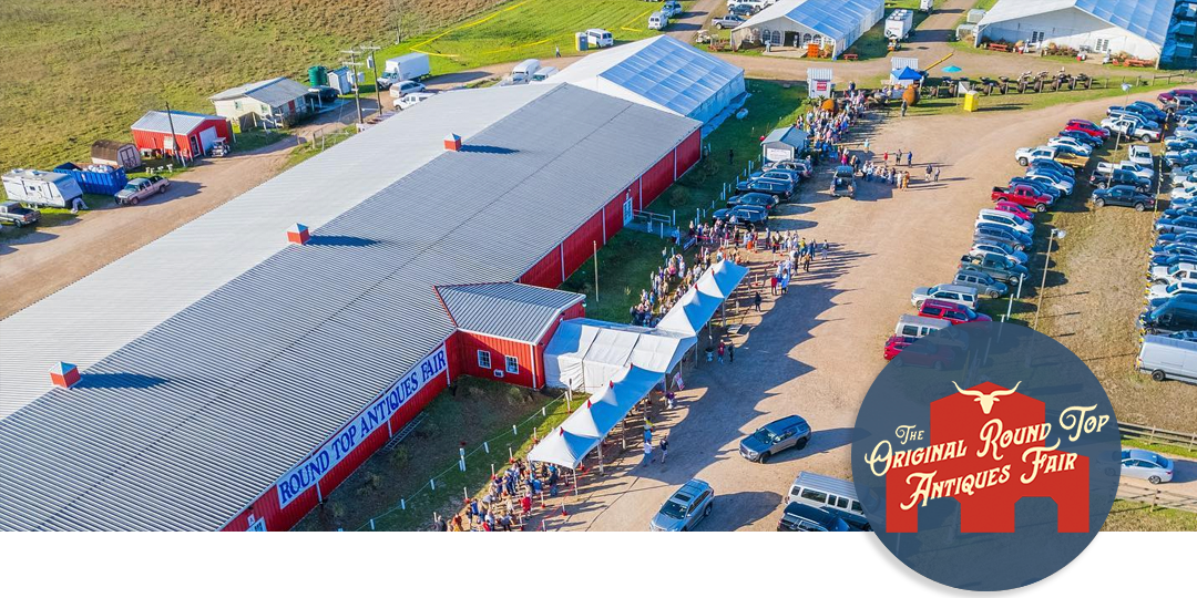 Aerial view of the Original Round Top Antiques Fair barns and show tents with cars parked and visitors arriving, showing the scale of the Texas event.