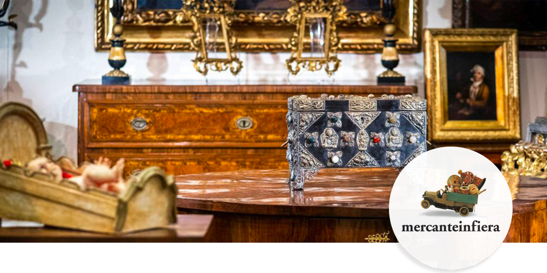 Dealer stand at Mercanteinfiera showing ornate wooden furniture and a jewel-encrusted Renaissance-style chest.