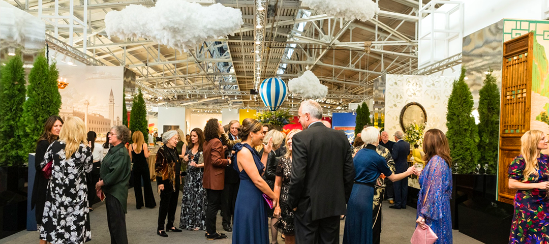 Opening night gala at the San Francisco Fall Show with guests in evening attire mingling beneath whimsical cloud and hot air balloon installations.