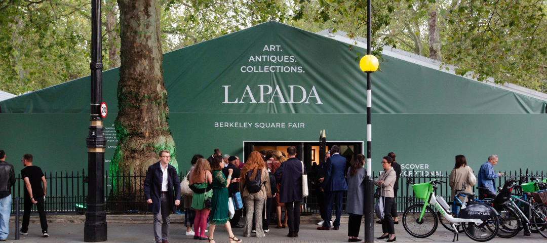 Guests gathering outside the green-and-white LAPADA Berkeley Square Fair pavilion beneath the trees of Mayfair, London.