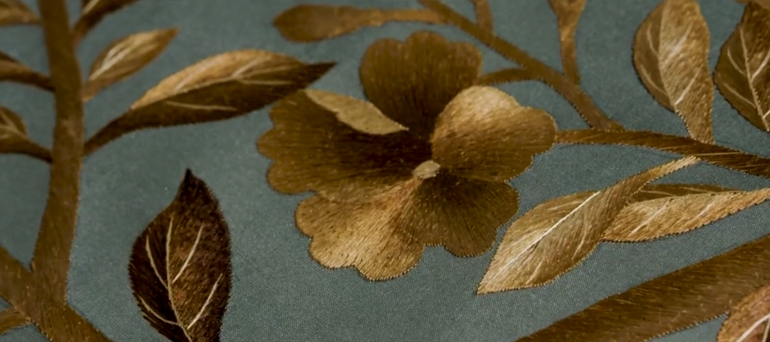 Close-up of gold floral embroidery on teal silk textile, highlighting craftsmanship and artistry featured at LAPADA Berkeley Square Fair.
