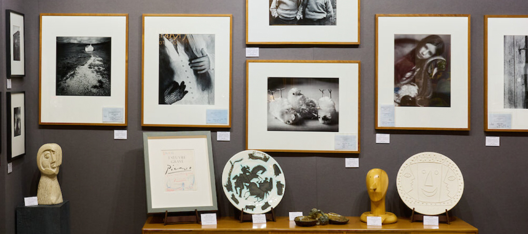 Gallery wall of framed black-and-white photography, ceramics, and sculpture on view at LAPADA Berkeley Square Fair.