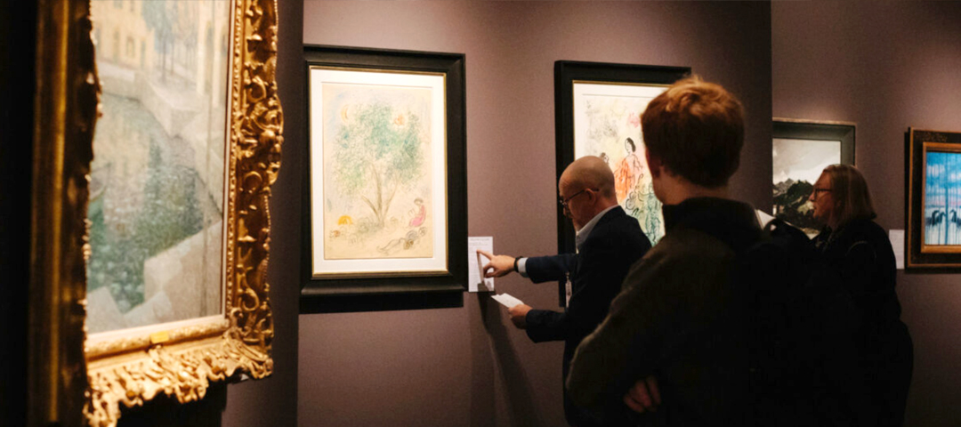 Visitors examining framed fine art and works on paper in one of LAPADA Berkeley Square Fair’s curated gallery spaces.