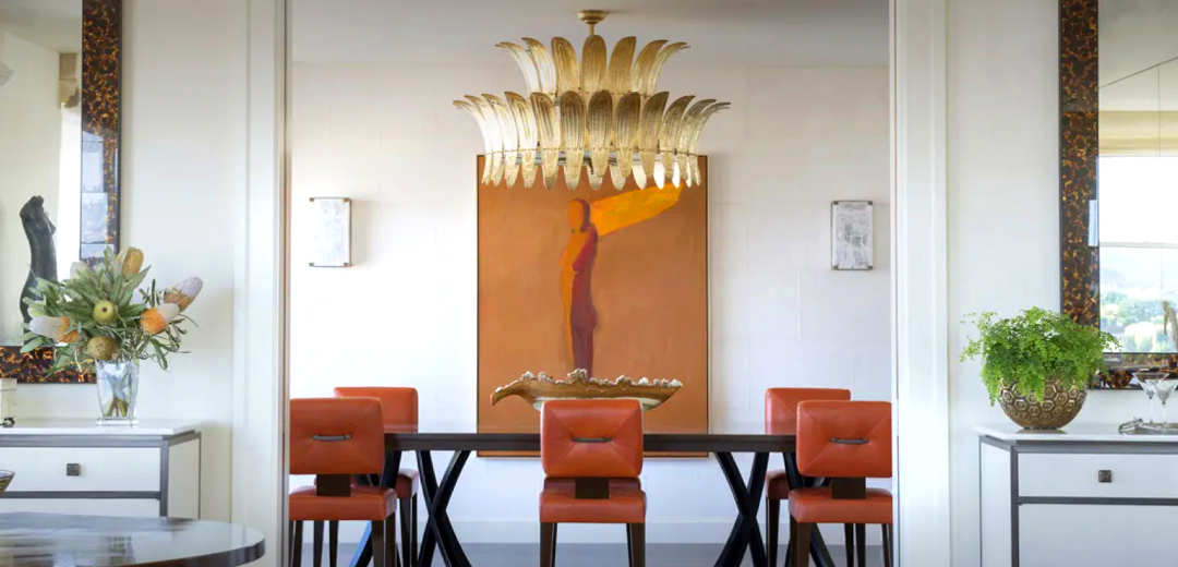 Elegant dining room designed by Suzanne Tucker featuring a sculptural gold chandelier, contemporary artwork, and vintage-inspired furnishings that blend modern lines with classic materials.